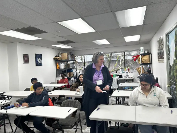 Competitors working at tables in a bright classroom.