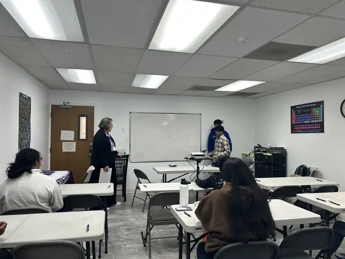 Students at tables in a classroom during a competition round.