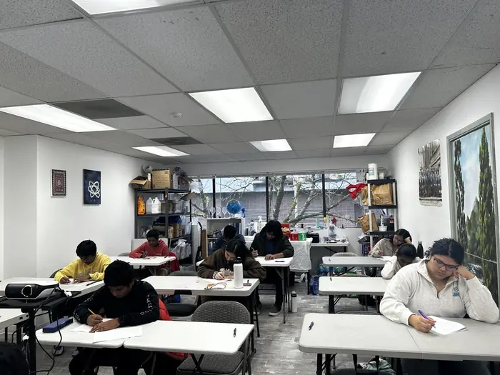 Competitors seated at tables across the room, heads down over their papers.