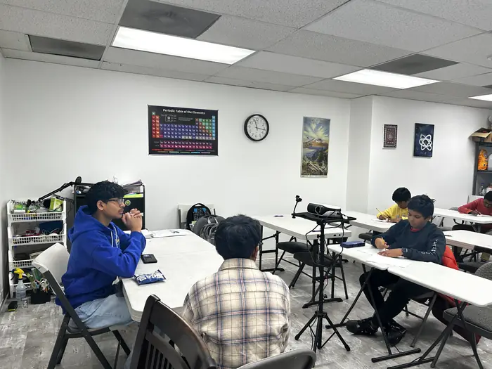 Students writing at tables during a round of the competition.