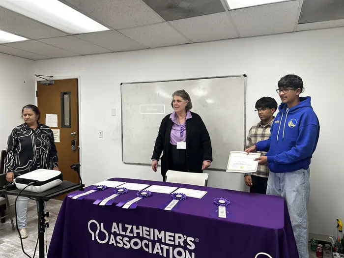 An organiser standing behind a table dressed in an Alzheimer's Association banner.