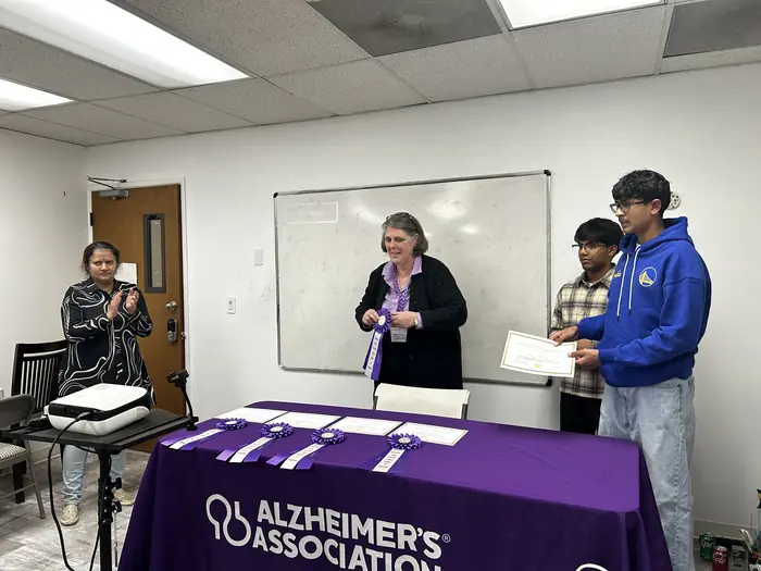 An organiser speaking to the room beside the Alzheimer's Association table.