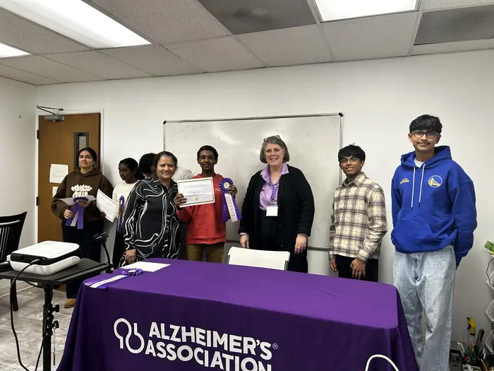 Competitors and organisers standing together behind the Alzheimer's Association table.