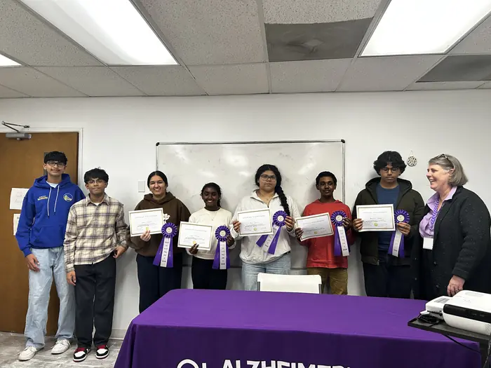 Competitors holding certificates with organisers behind the Alzheimer's Association table.