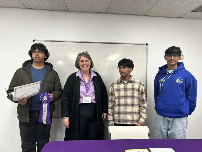Certificate winners standing with an organiser behind the Alzheimer's Association table.
